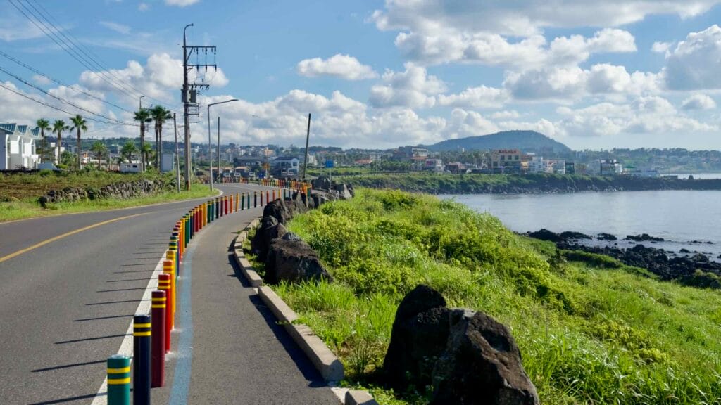 Colorful posts mark the bikeway along the curving Aewol coastline.