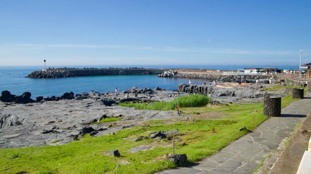People walking across basalt flats and traditional saltpans at Gueom Port.