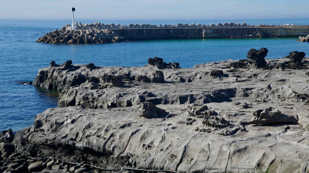 Undulating basalt platform and tide pools beside the breakwater at Gueom Port.
