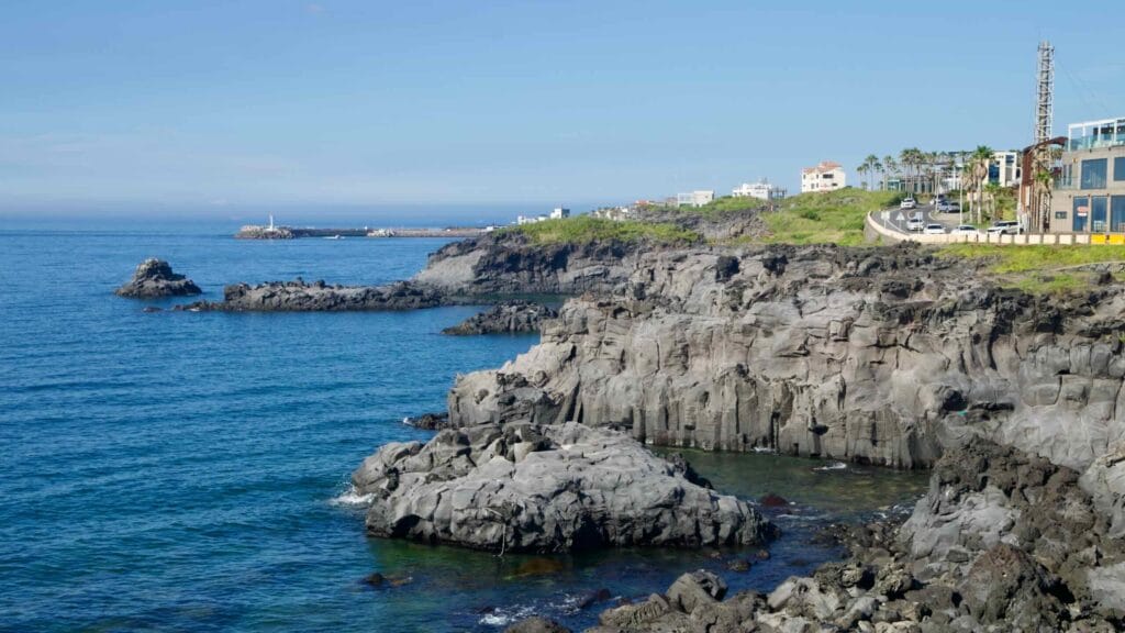 Layered basalt cliffs near Gueom with the harbor entrance in the distance.