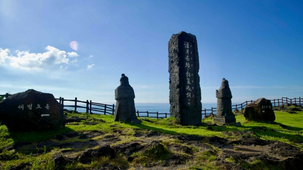 Tall basalt monuments and guardian figures rise on a headland at Darak Shelter.