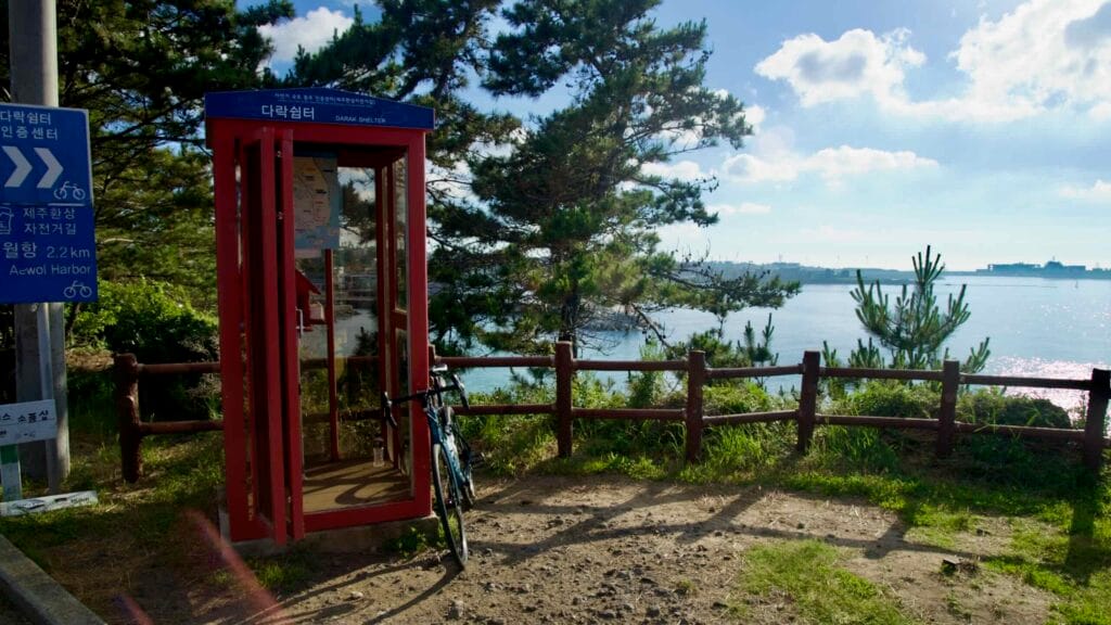 Red Darak Shelter phone‑booth certification point stands on a bluff above the sea.