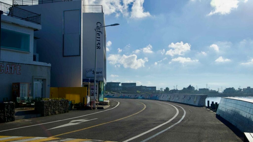 A coastal road curves beside a mosaic seawall at the edge of Gonae Port.