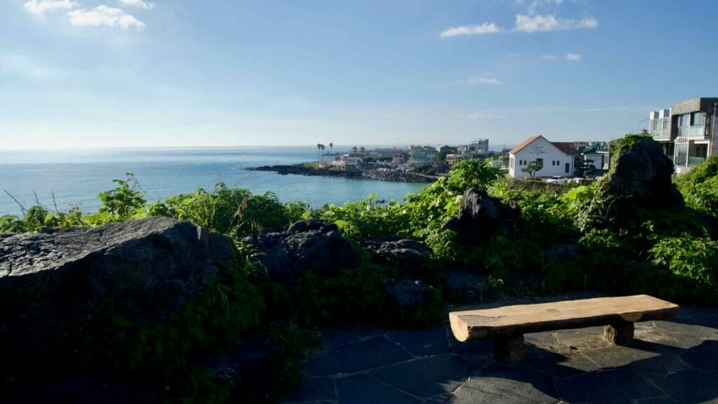 A wooden bench sits among lava rocks at Aewol Handam Park.