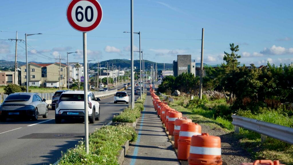 Traffic flows past a 60‑kilometer speed limit sign on the coastal highway.