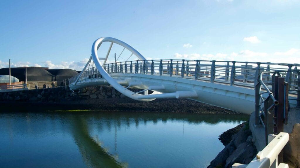 The ringed Bidan pedestrian bridge crosses a calm inlet near Geumseong Port in Jeju.