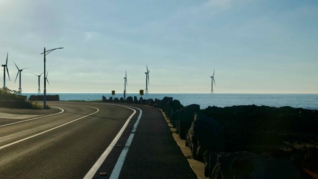 Curving coastal road by Gwideok with offshore wind turbines on the horizon.