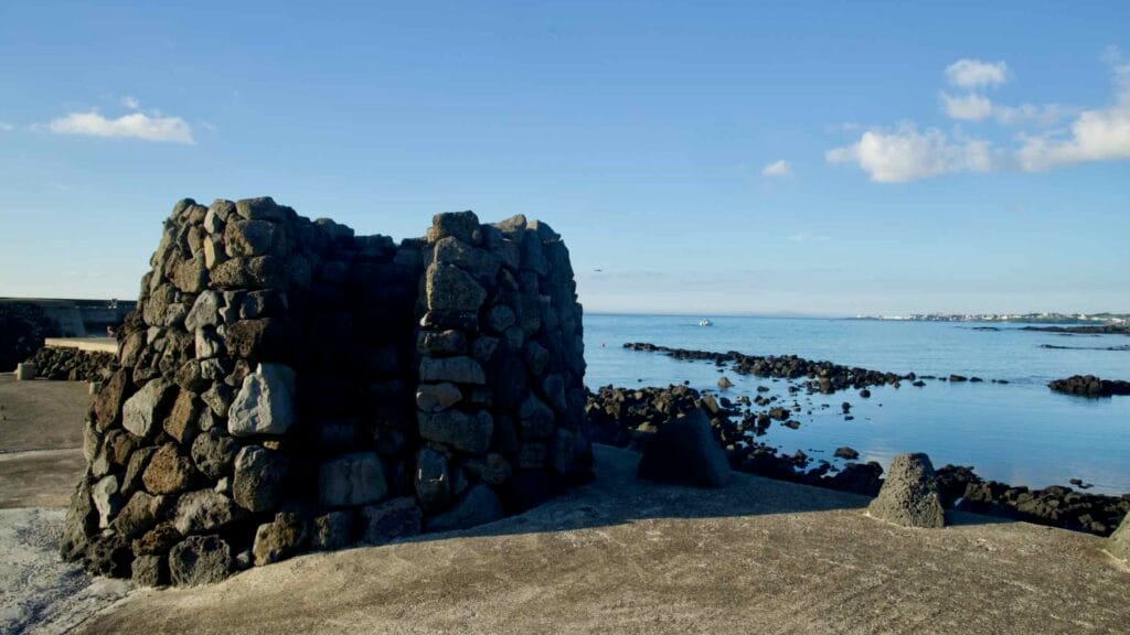 Circular lava‑stone structure beside basalt fish weirs at Gwideok Village.