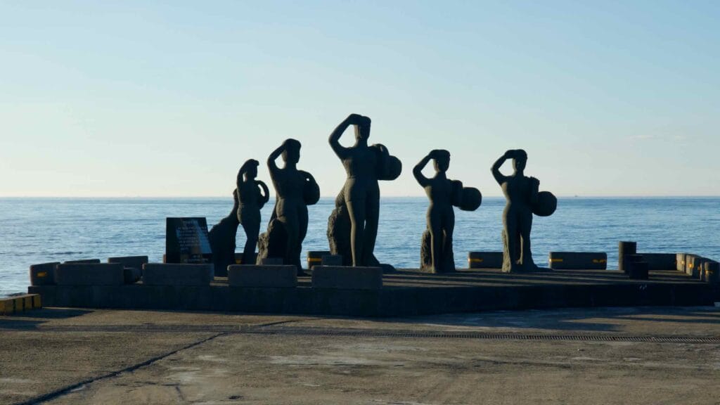Haenyeo diver statues line the pier at Hansupul Haenyeo School by the open sea.