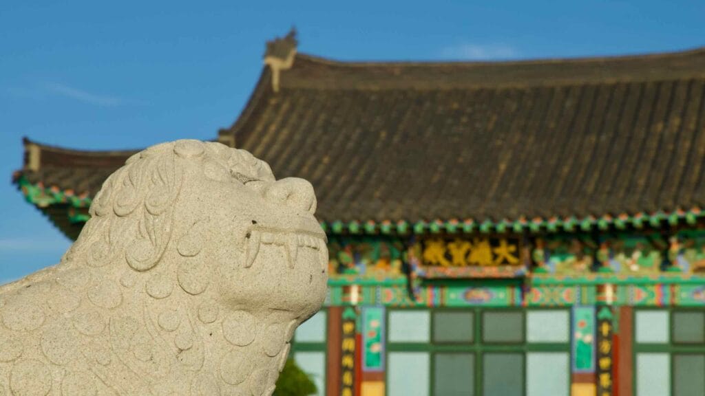 Carved stone guardian lion with Haewoon Temple’s main hall behind.