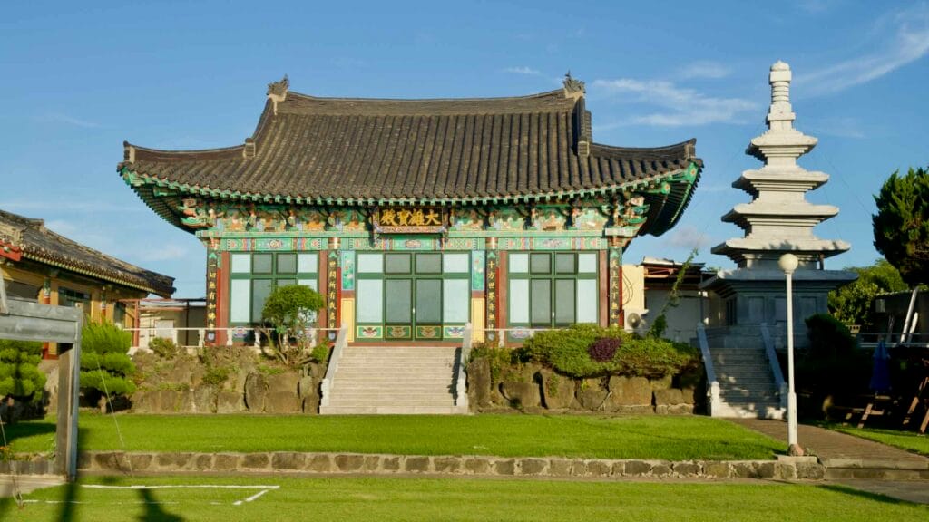 Haewoon Temple main hall and stone pagoda under a bright Jeju sky.
