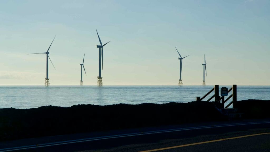 Row of offshore wind turbines turning above calm seas off Jeju’s northwest coast.