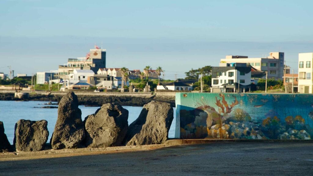 Underwater‑scene mural on a harbor wall stands behind jagged basalt posts.