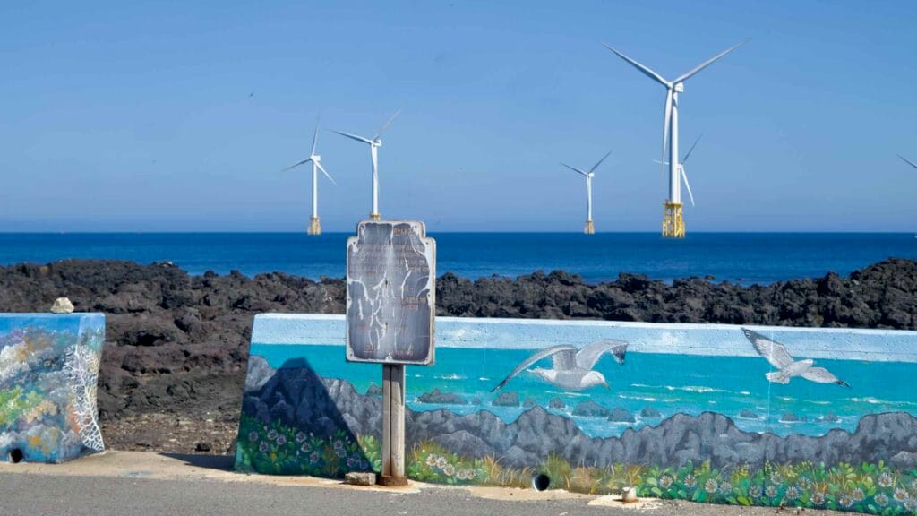 A rusted coastal map sign stands before a painted seawall.