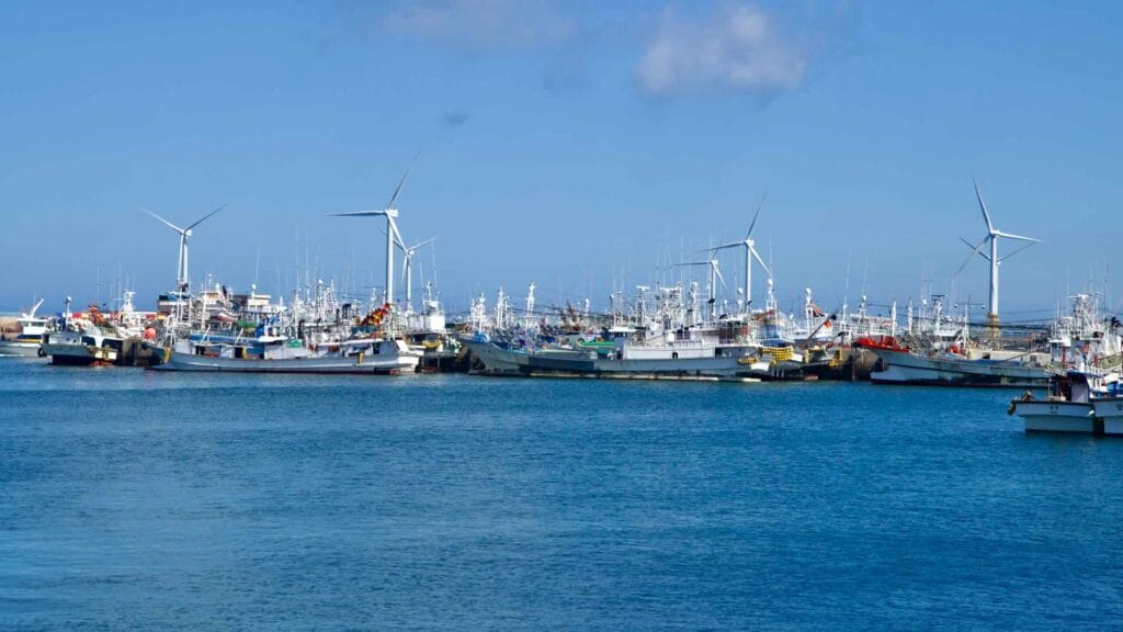 Tight cluster of fishing boats at Hanlim with windmills offshore.
