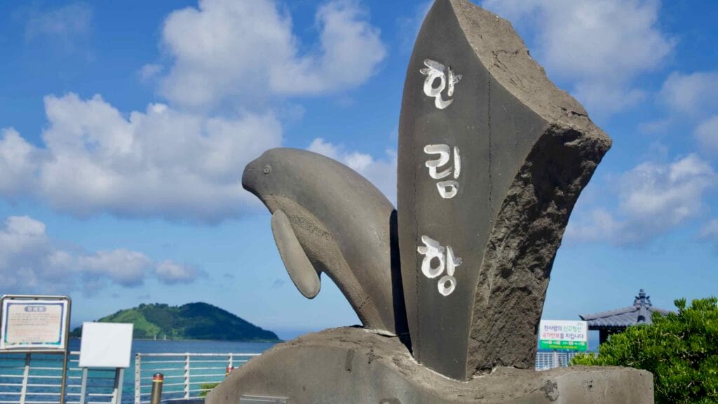 Basalt dolphin monument marking Hanlim Port with Biyangdo beyond.