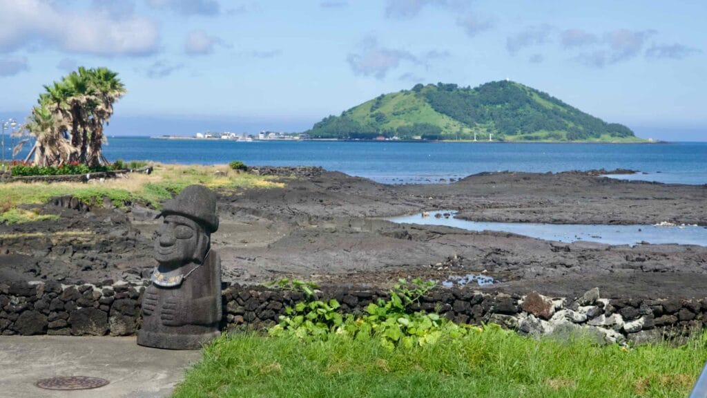 Dol hareubang with Biyangdo Island beyond the lava flats.