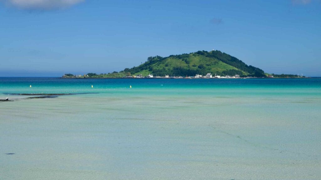 Turquoise shallows at Hyeopjae Beach with Biyangdo beyond.