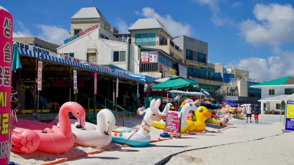 Colorful inflatable rentals line the beach outside Hyeopjae shops.