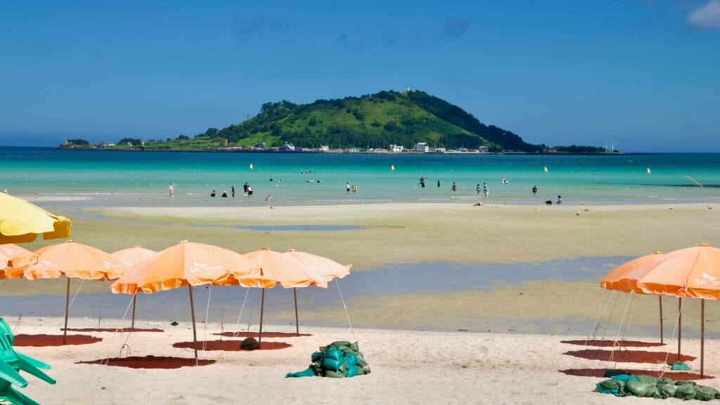 Orange parasols at Hyeopjae with Biyangdo Island beyond.