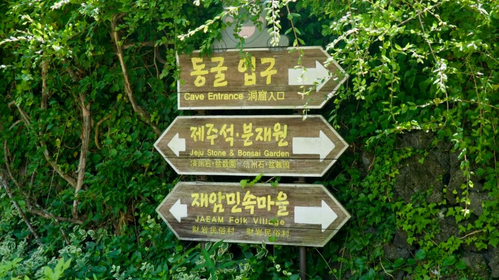 Hallim Park wooden direction signs show cave, bonsai garden, and folk village.