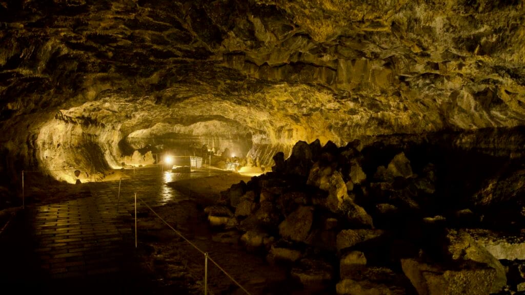Wide chamber with boulders and lit exhibits inside Hallim Park’s lava cave.