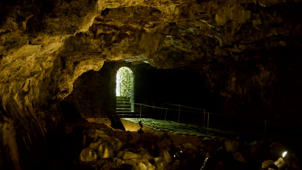 Backlit arch and steps at the end of a Hallim Park lava cave chamber.