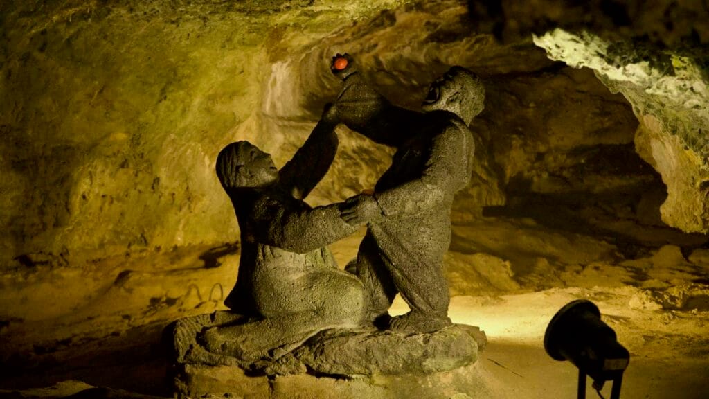 Basalt statues displayed inside the Hallim Park lava cave under gallery lighting.