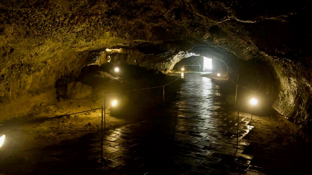 Glowing exit at the end of a lava-tube corridor with reflective tiles, Hallim Park.