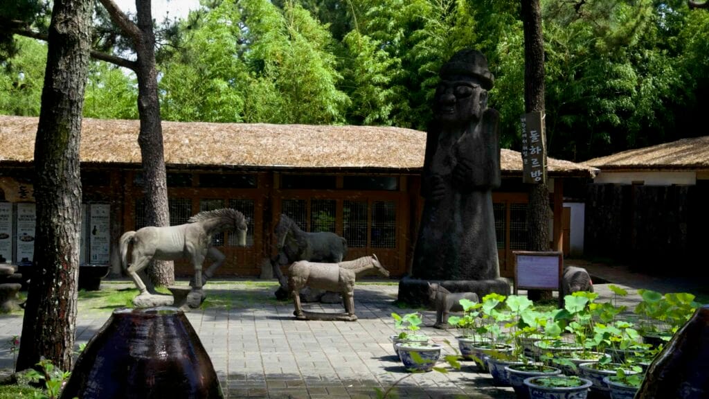 Dol hareubang statue, stone horses, and lotus pots in Hallim Park’s courtyard.