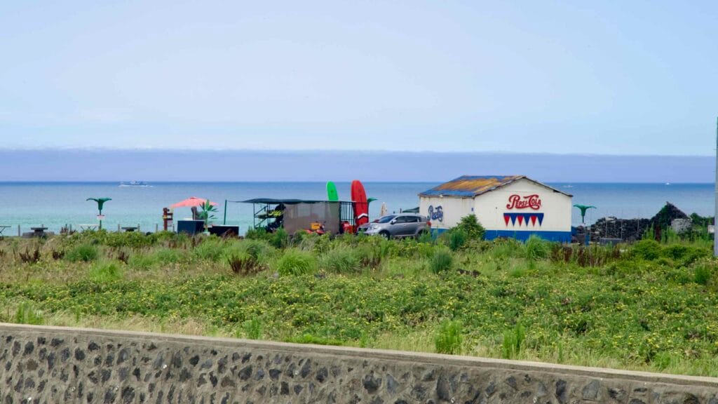 Seaside shack with Pepsi sign and surfboards near Woldeok‑ri.