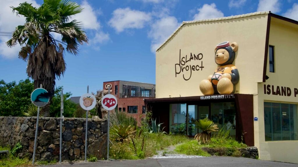 Island Project storefront near Sinchang with bear sculpture and Jeju logo.