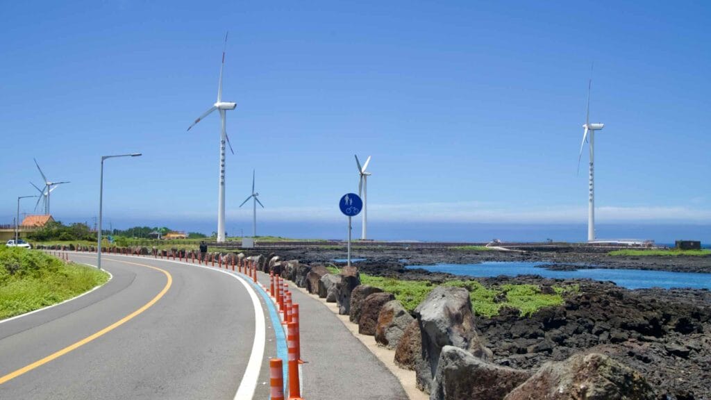 Shared path along Sinchang’s coastal road with turbines and lava shore.