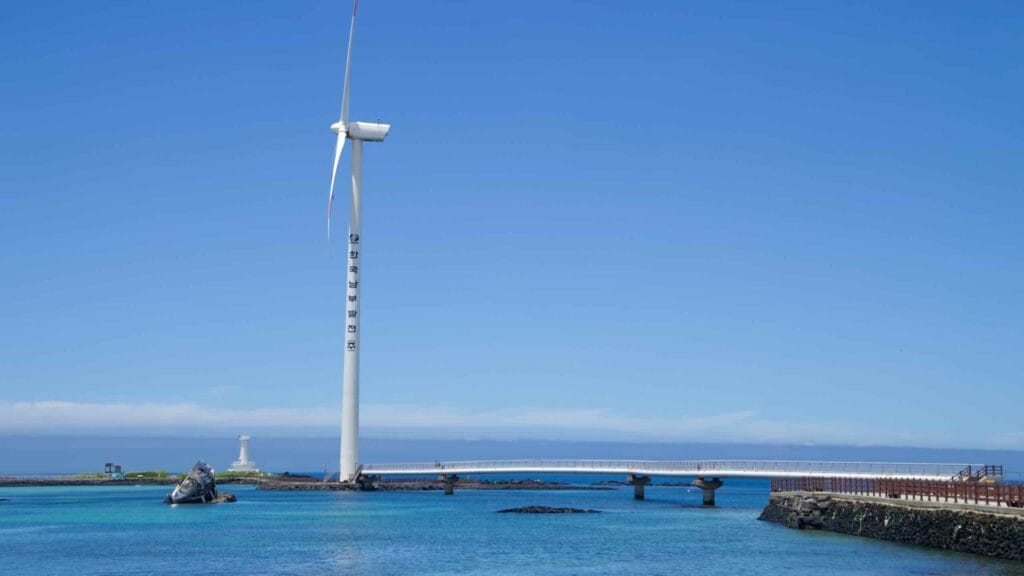 A wind turbine rises beside the raised footbridge over clear water at Sinchang.