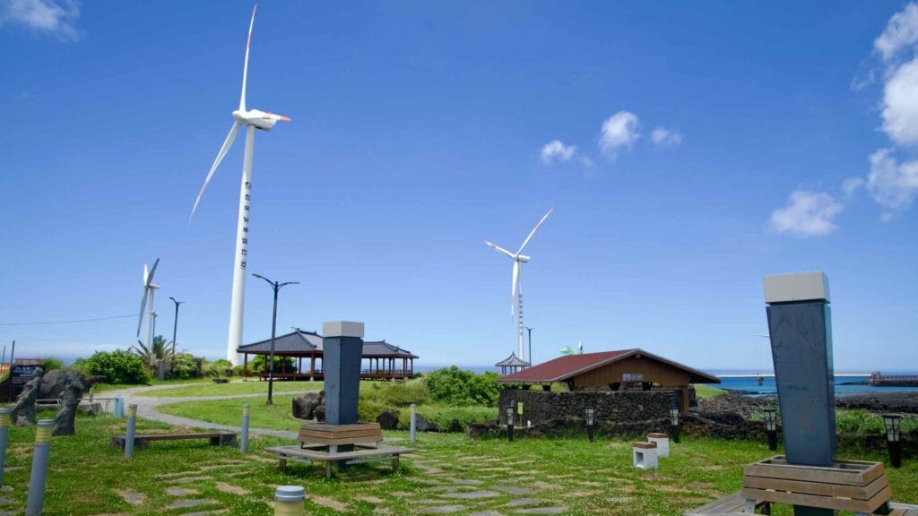 Gazebos and park paths beneath tall wind turbines at Sinchang.
