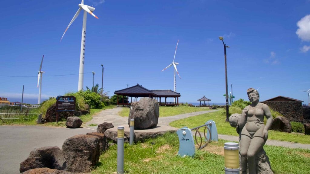 Haenyeo statue and pavilion under tall wind turbines at Sinchang.