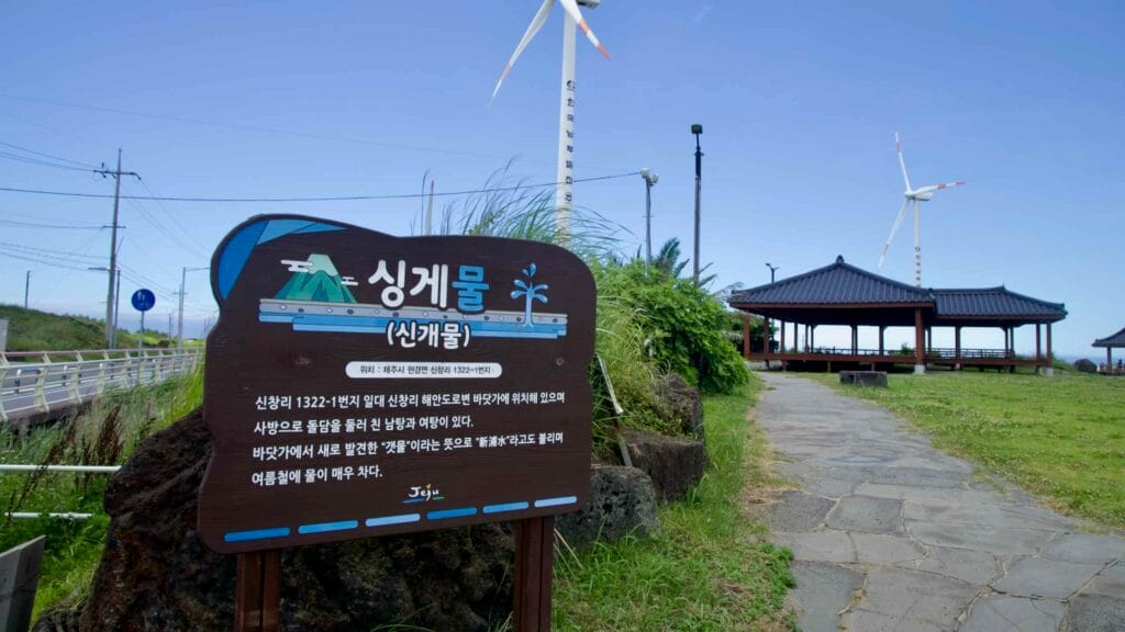 Singgemul sign and pavilion with turbines turning above the coast.