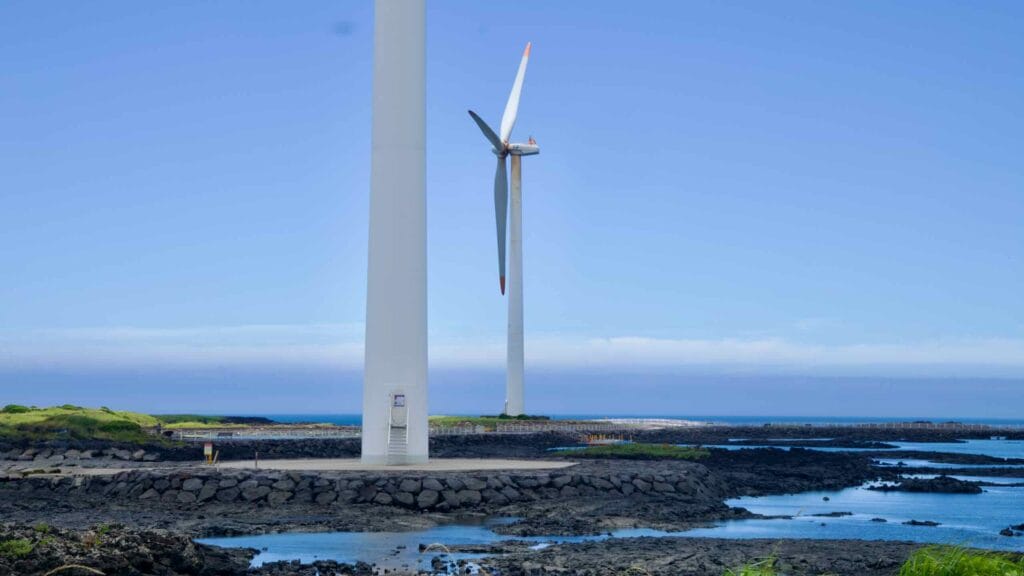 Wind turbines over basalt inlets and tide pools near the tower bases.
