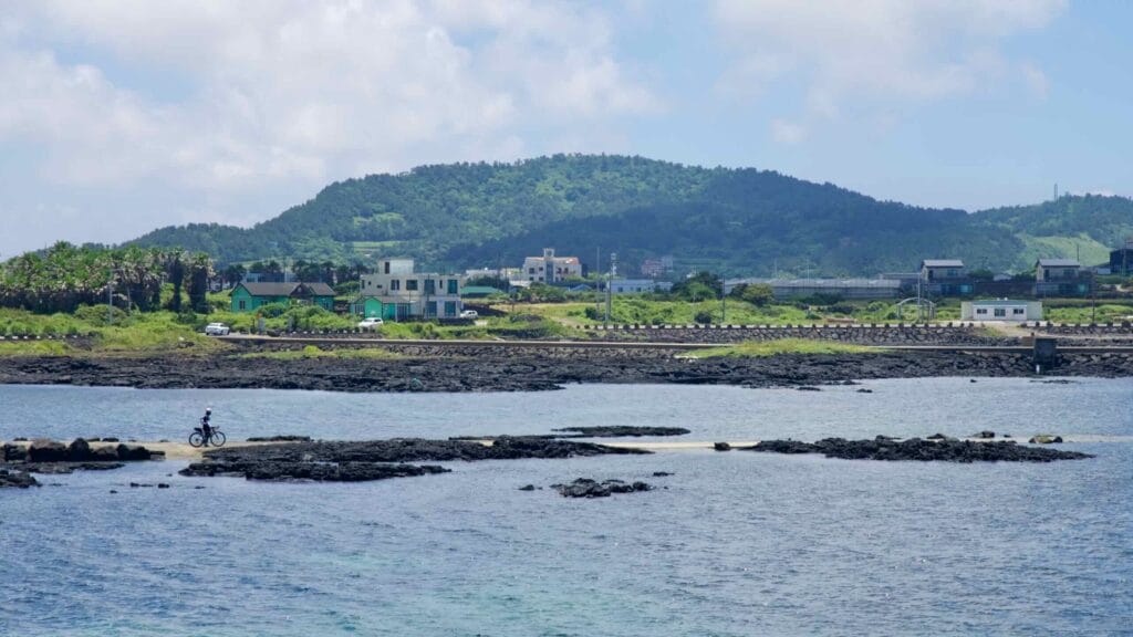Cyclist rides a narrow spit by reef pools near Yongsu.