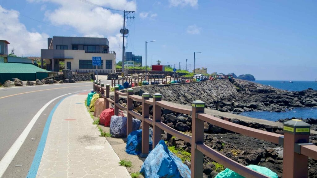 Colored boulders line the coastal bike lane near village houses.