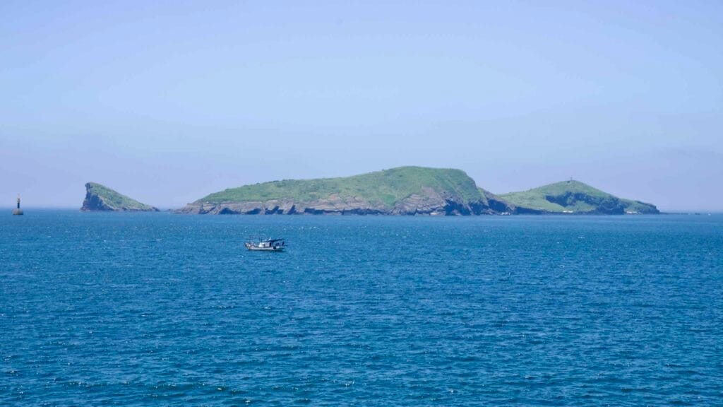 Fishing boat off Chagwido with layered coastal cliffs.