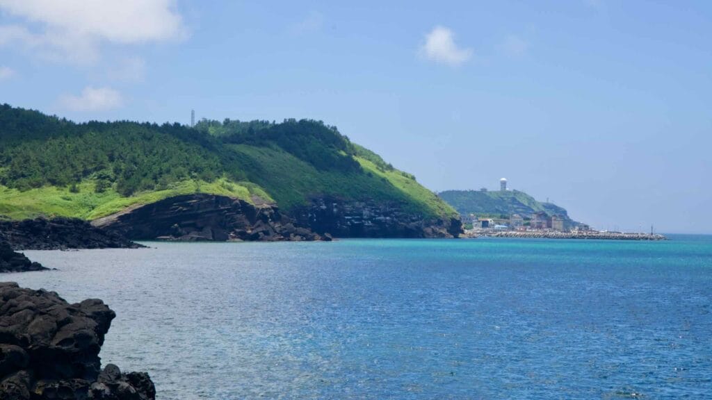 Suwolbong seen from Dangsanbong, with cliffs, harbor, and a radar dome on the ridge.
