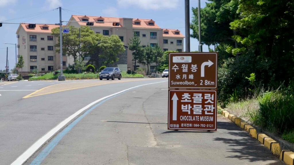 Pine‑covered hills around Albong above fields on Jeju’s western shoreline.