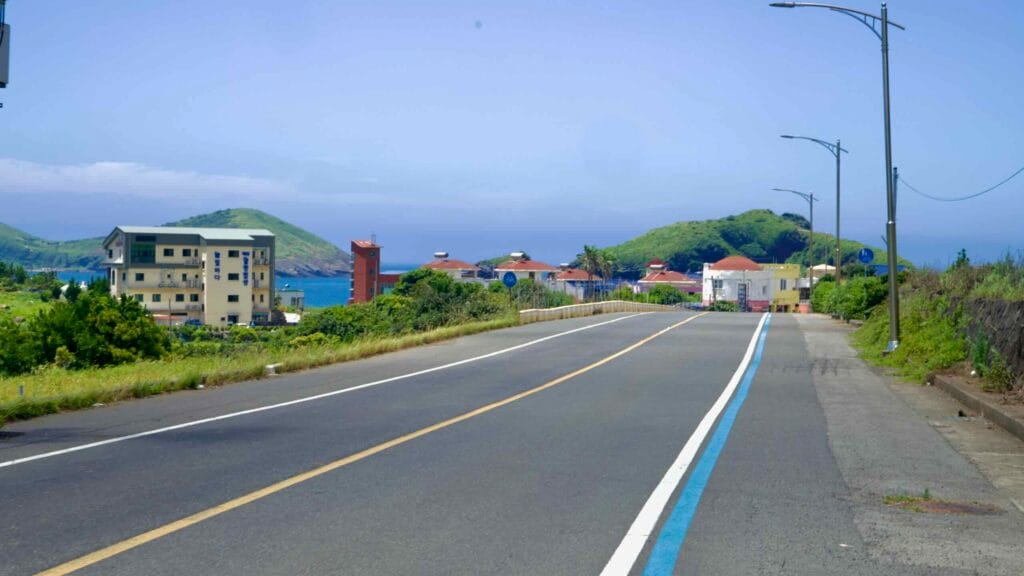 Road descending toward Chagwido Port with green islet ahead.