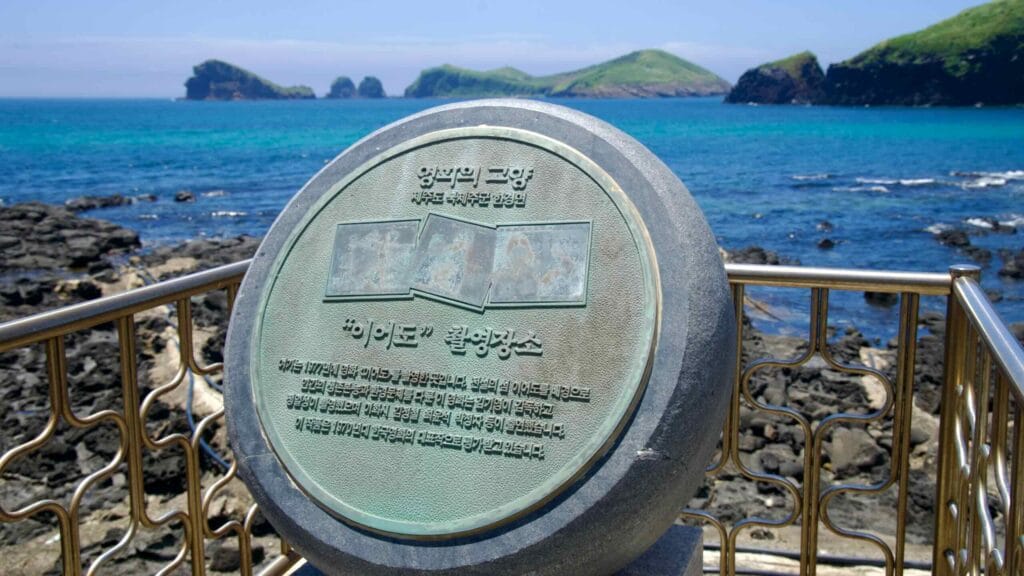 Round plaque marking a film location with offshore islets beyond.