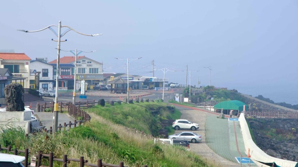 Coastal shops and a parking terrace above the basalt shore along Brother’s Coast Road at Sagye.