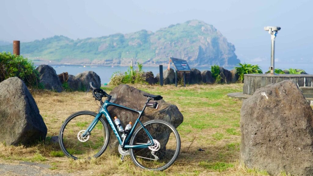 Road bike at the Sagye Port lookout with a volcanic headland across the bay.