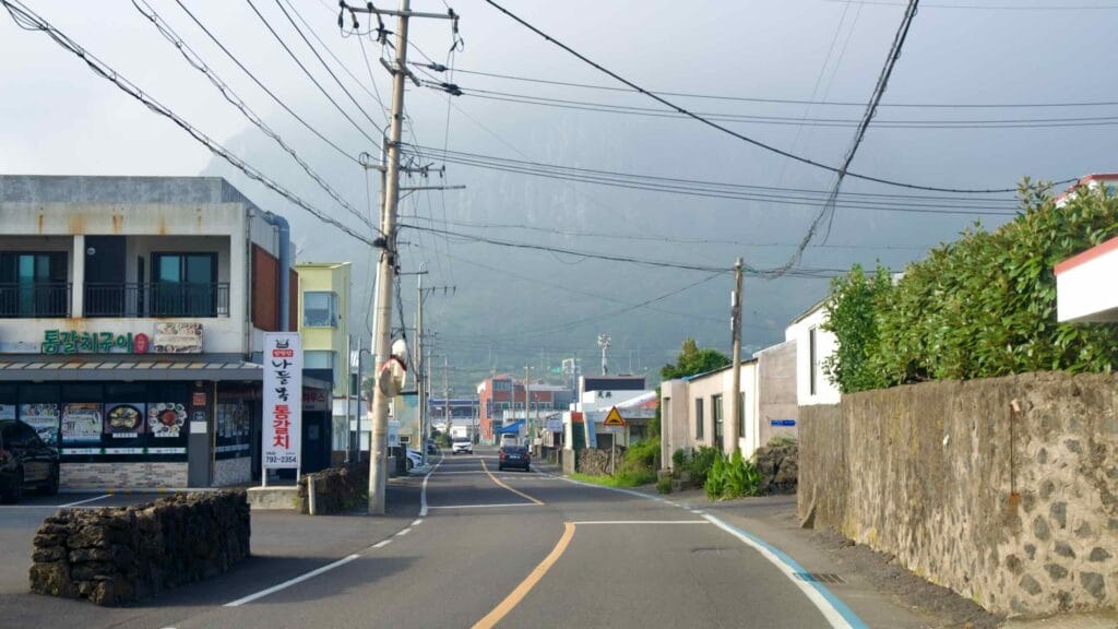 Sagye village street leading toward hazy Sanbangsan cliffs.