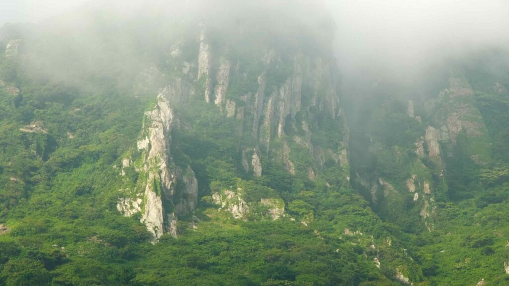 Sanbangsan’s steep buttresses cut into cloud above summer greenery.