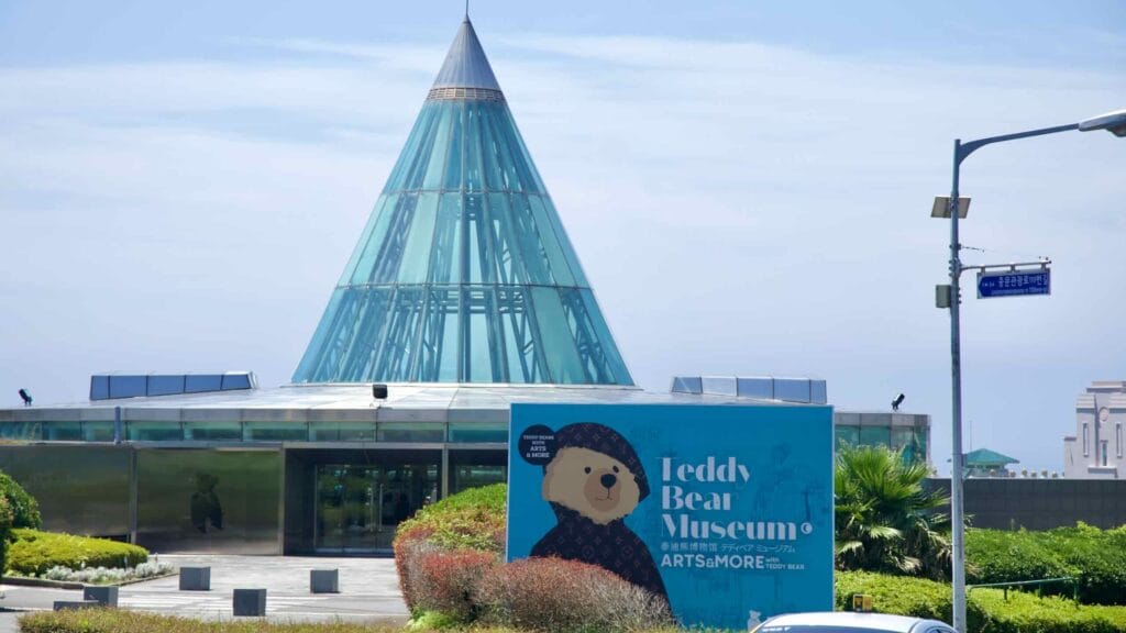 The Jungmun Teddy Bear Museum features a glass cone atrium and a large graphic sign near the entrance.